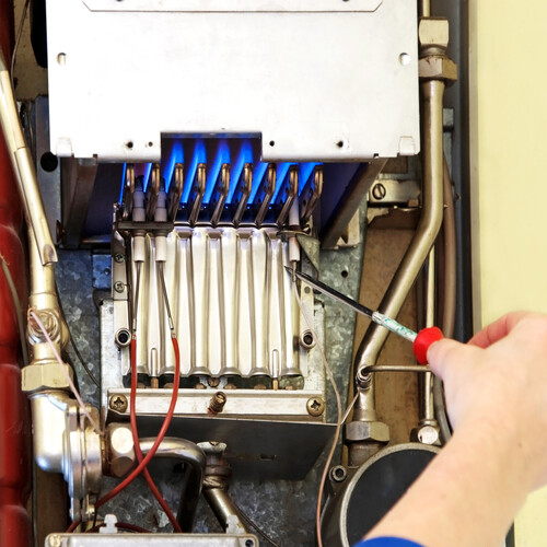 hands of a plumber repairing a gas furnace